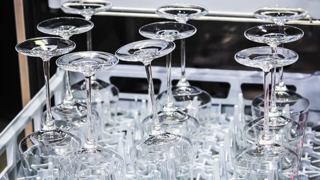 Verres à vin placés tête en bas dans le panier supérieur d'un lave-vaisselle moderne ouvert, chargement correct visible
