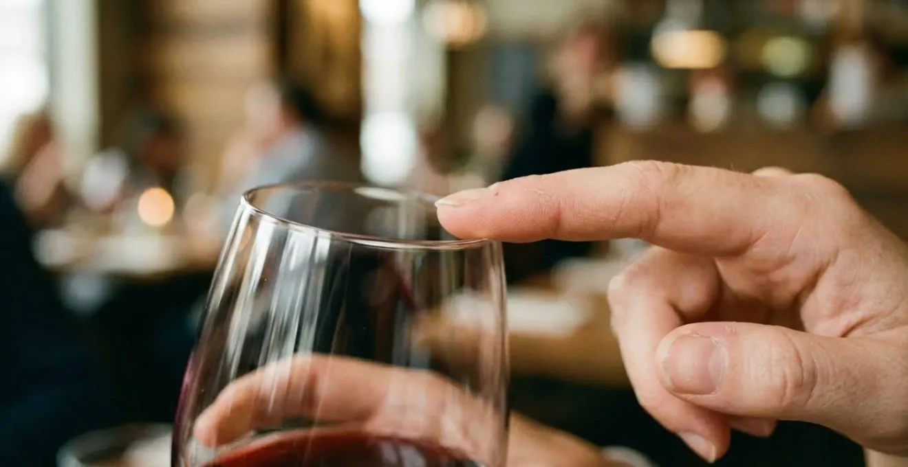 Gros plan sur le bord très fin d'un verre à vin avec un doigt effleurant délicatement le buvant